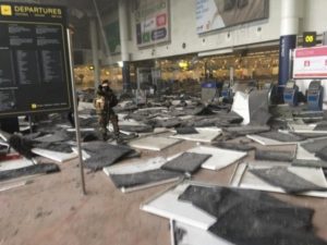 Policial permanece de guarda na área de embarque do Aeroporto Internacional de Zaventem, em Bruxelas, na Bélgica, onde duas bombas foram detonadas – Foto: The Int'l Spectator/Reprodução